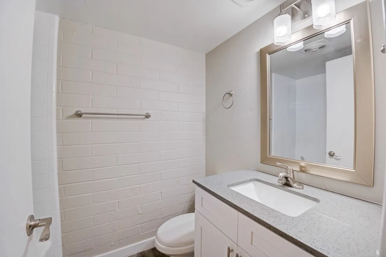 Bathroom, white subway tile shower, white vanity cabinetry, quartz countertop, framed mirror