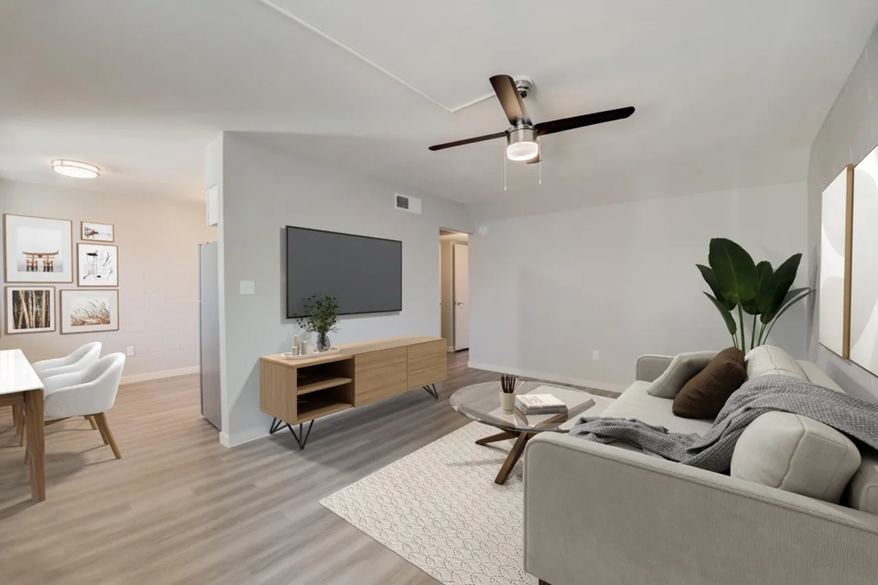 Living room, wood-style plank flooring, ceiling fan, mounted flat-screen TV, upholstered seating