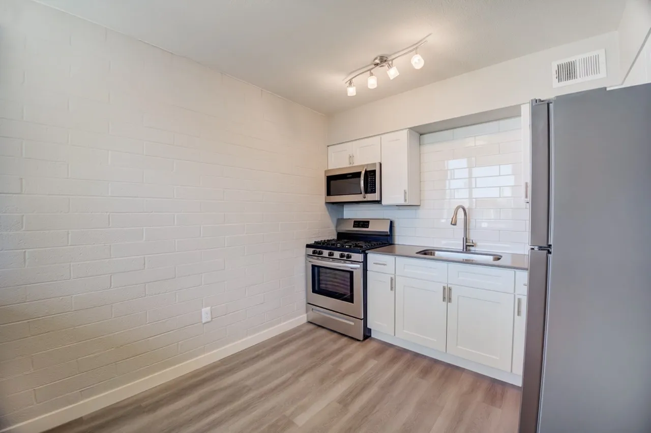 Kitchen, white shaker cabinetry, stainless steel appliances, wood-style plank flooring, granite countertops