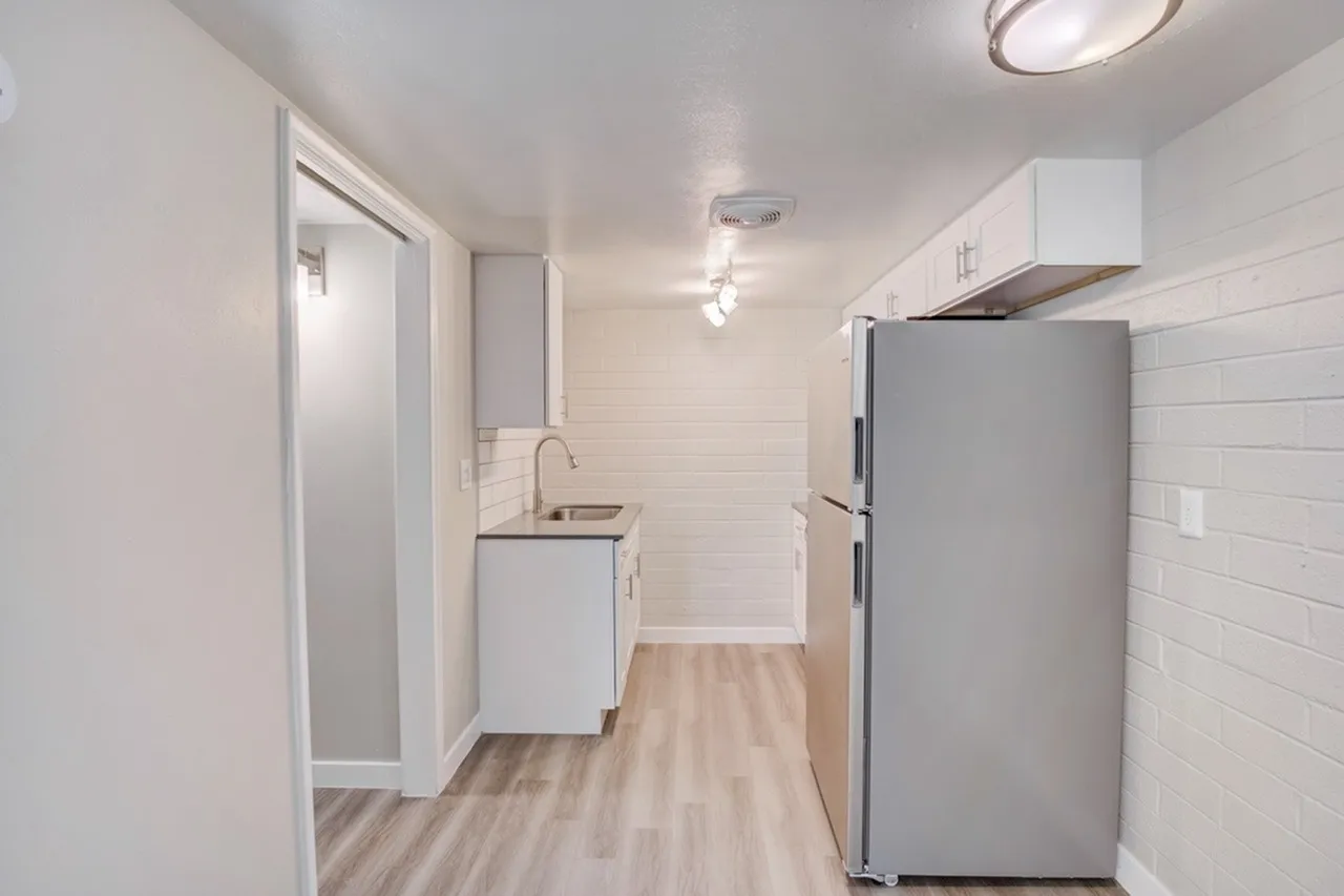 Kitchen, white cabinetry, stainless steel refrigerator, wood-style plank flooring