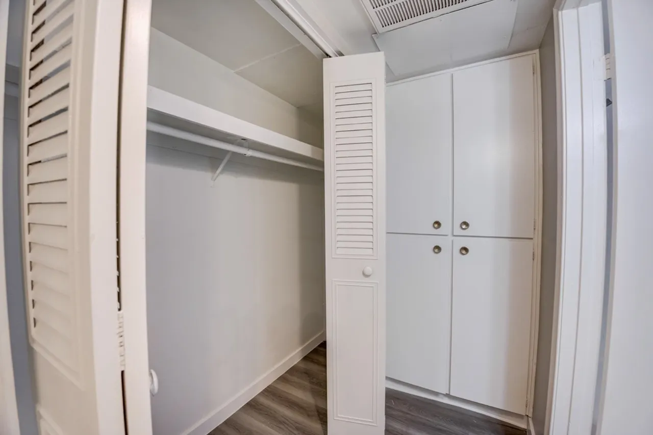 Walk-in closet, white louvered doors, shelving, wood-style plank flooring