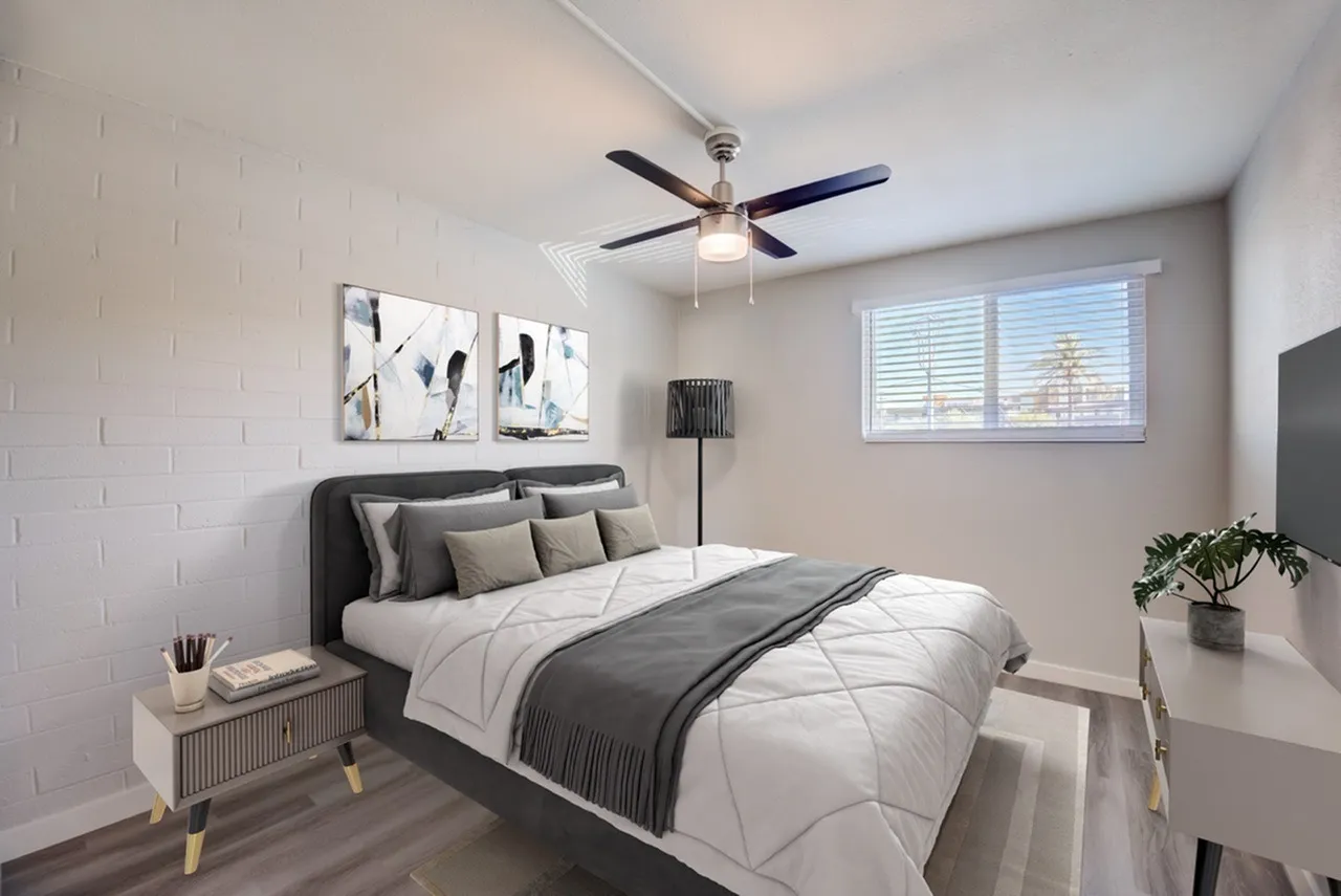 Primary bedroom, gray upholstered bed, wood-style plank flooring, ceiling fan with light fixture