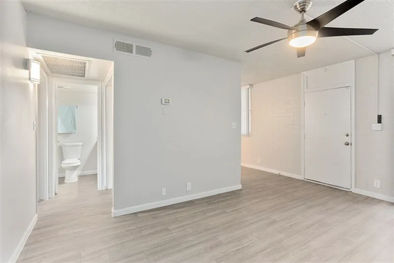 Primary bedroom, wood-style plank flooring, ceiling fan with light, white walls