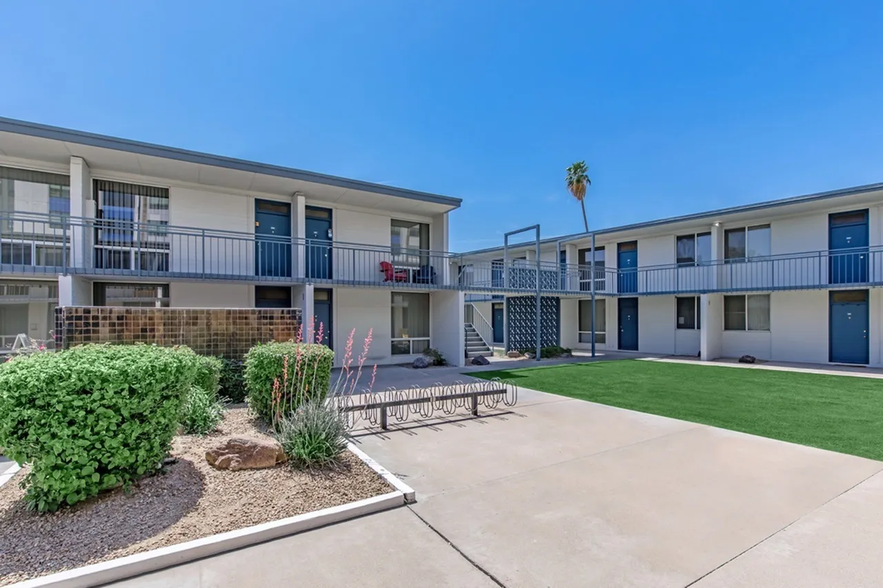Exterior courtyard, manicured lawn, metal benches, landscaping, palm tree