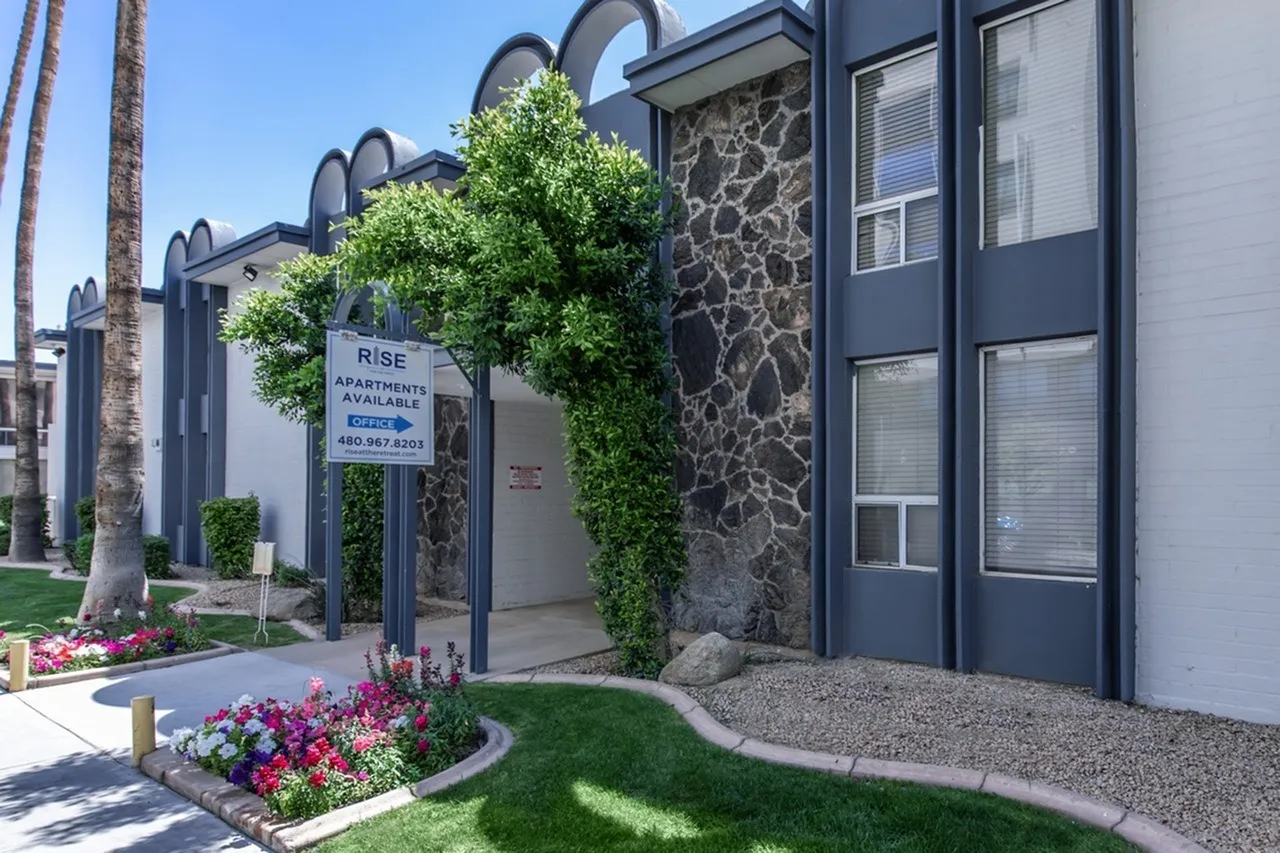 Apartment building entrance, arched doorway, ivy-covered wall, flowering landscape