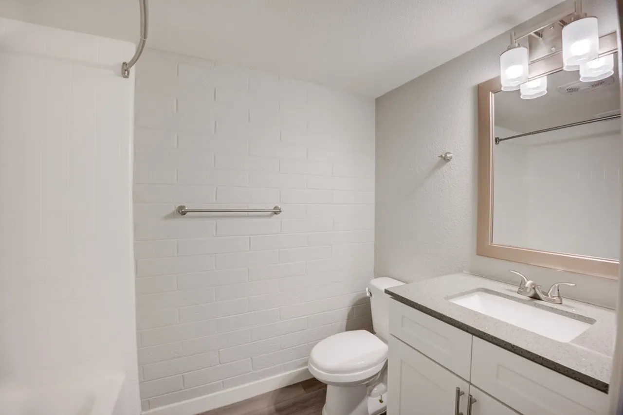 Bathroom, white subway tile shower, single vanity with sink, mirror with lighting