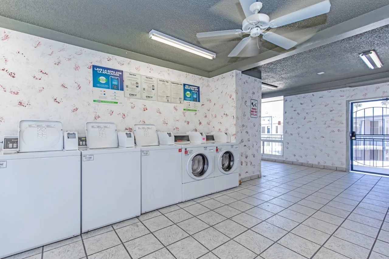 Laundry room, white washer and dryer, tile flooring, ceiling fan, informational signage on walls