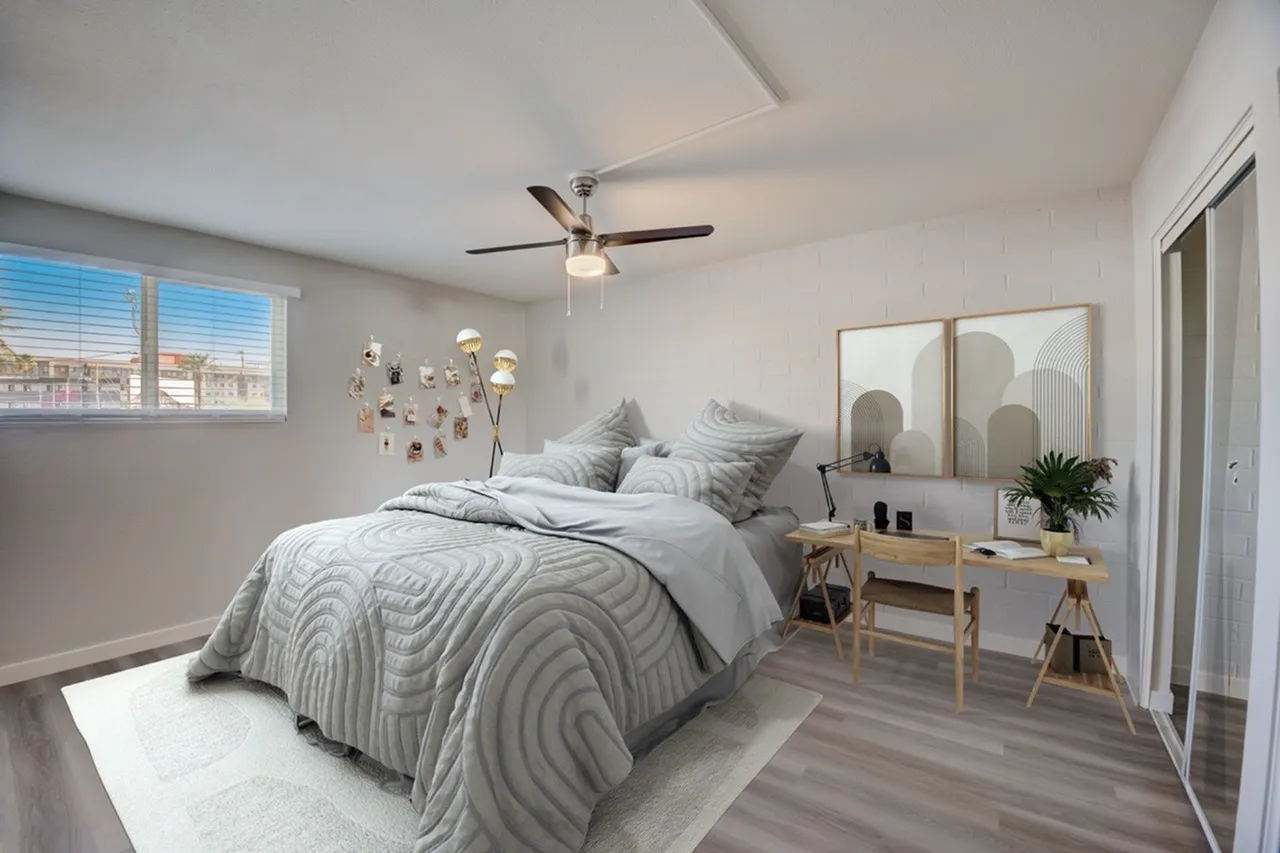 Primary bedroom, wood-style plank flooring, ceiling fan, vanity desk with mirror, striped bedding