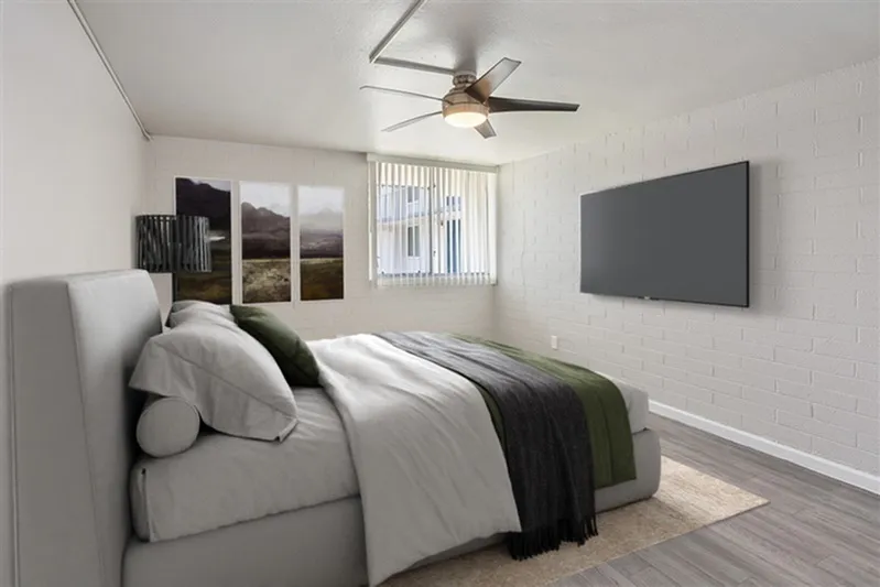 Primary bedroom, wood-style plank flooring, ceiling fan, wall-mounted TV, upholstered bed