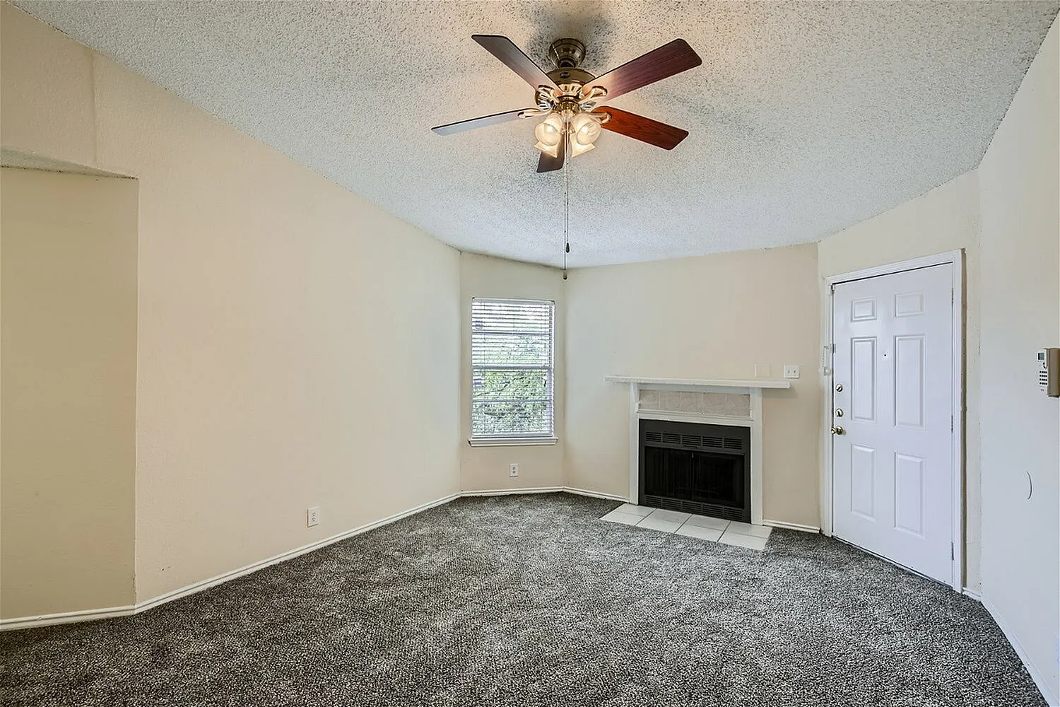 Living room, gray carpet flooring, ceiling fan with light fixture, fireplace, white entry door