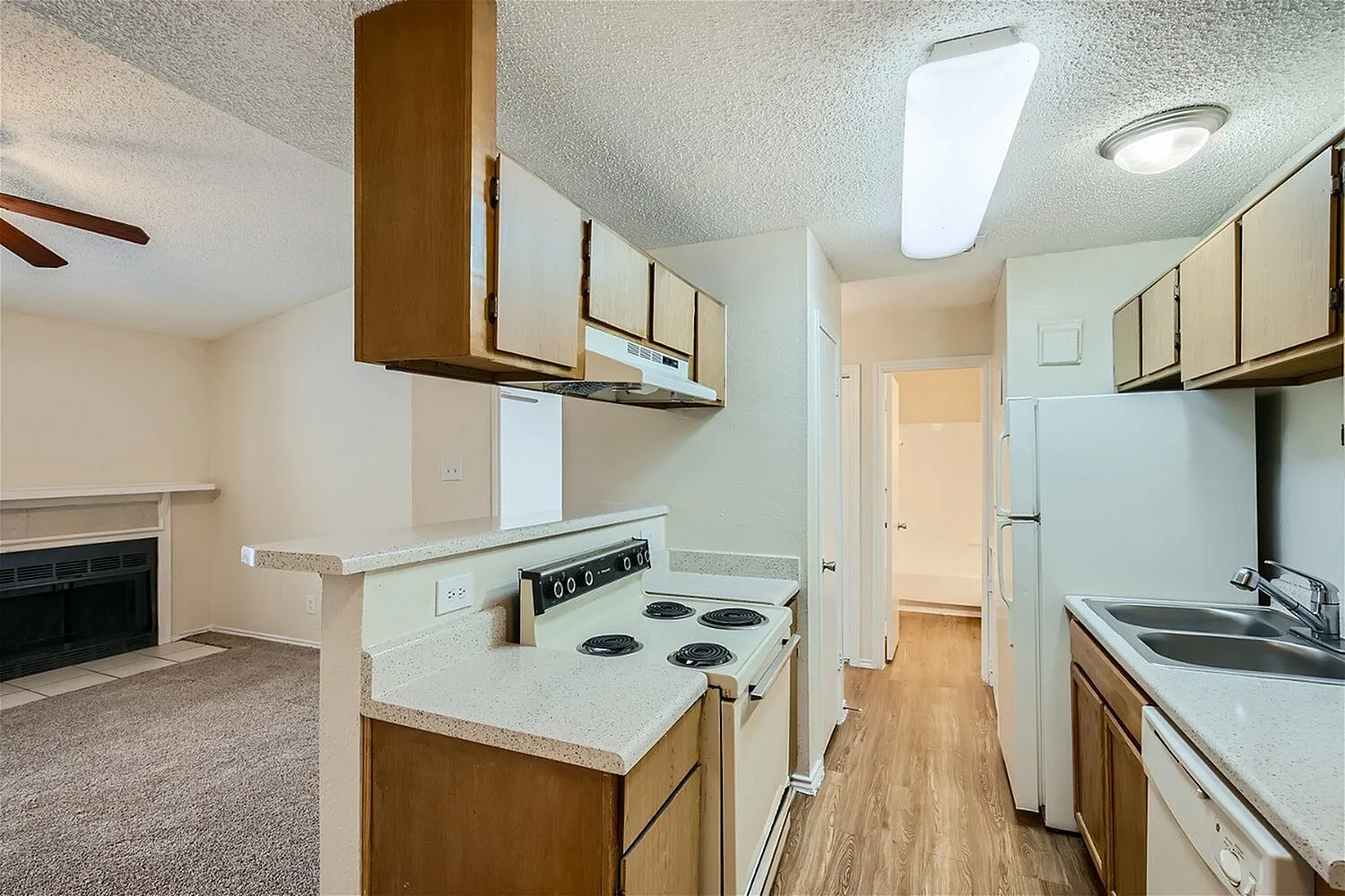 Kitchen, wood cabinetry, white countertops, electric range, wood-style plank flooring