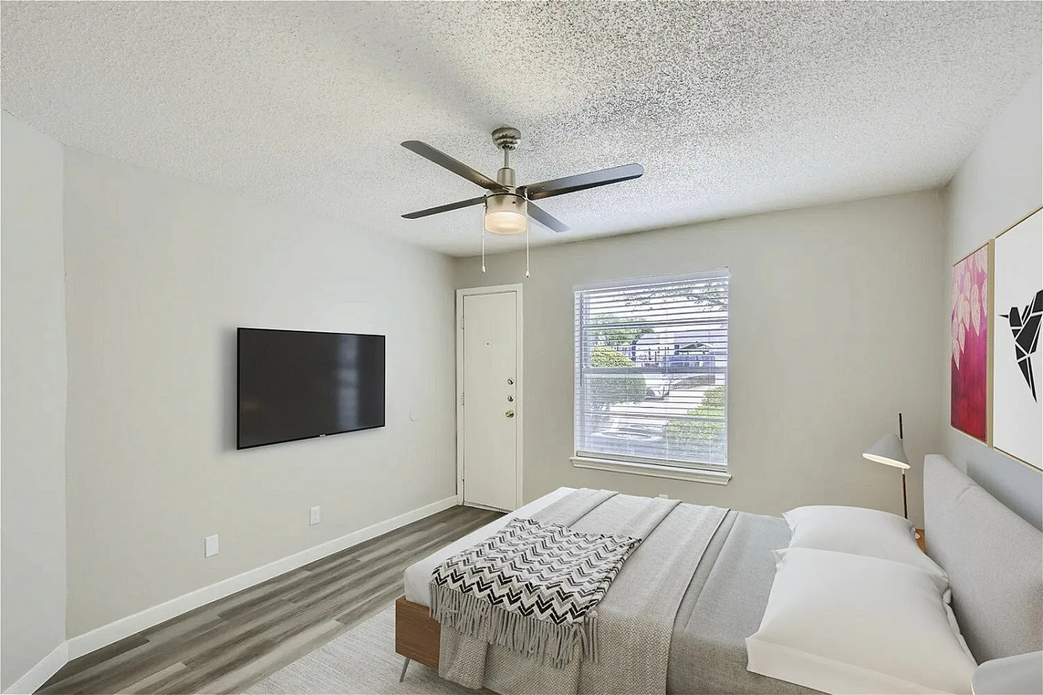 Primary bedroom, wood-style plank flooring, ceiling fan, wall-mounted TV, glass door