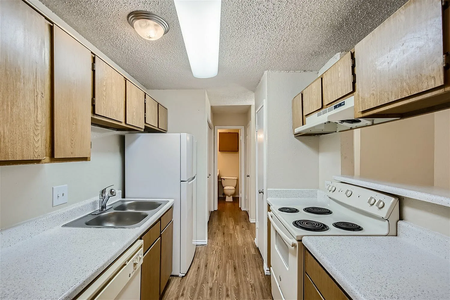 Kitchen, wood cabinetry, white appliances, wood-style plank flooring, countertops