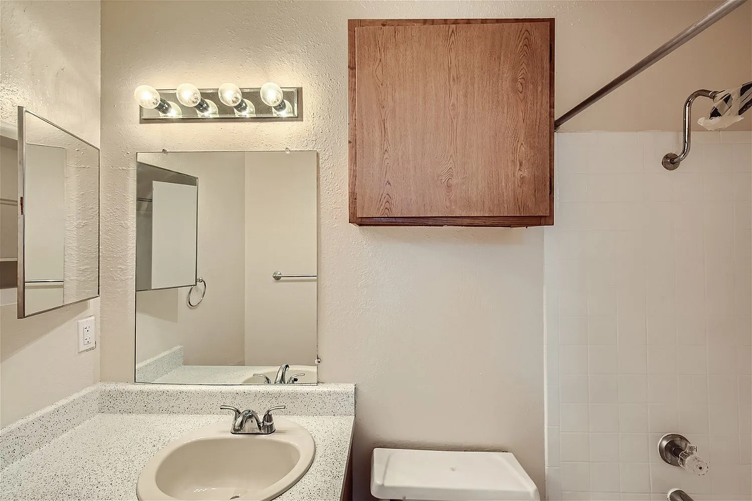Primary bathroom, round pedestal sink, quartz countertop, framed mirror, wooden medicine cabinet