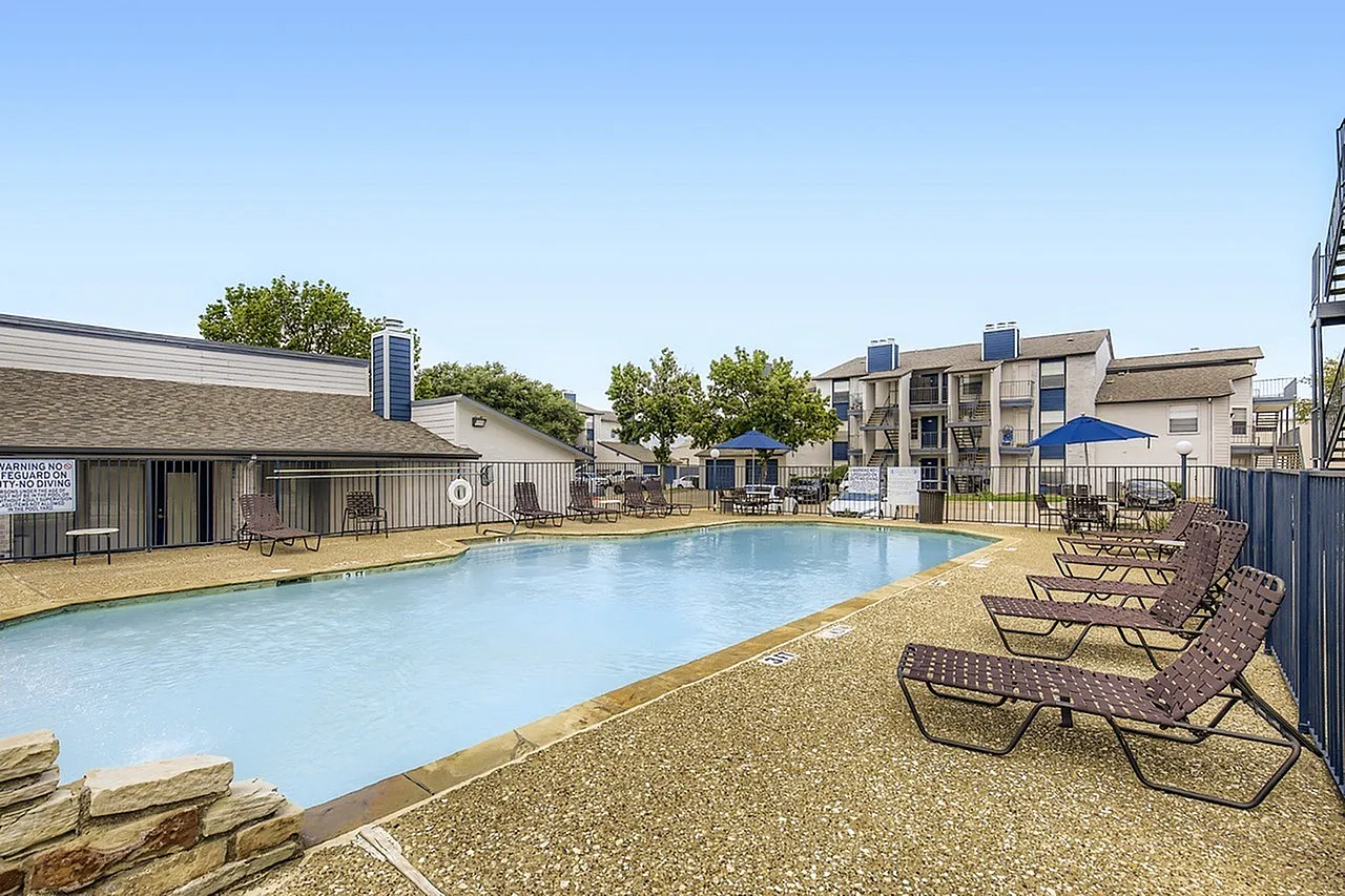 Swimming pool, lounge chairs, blue umbrella, concrete deck