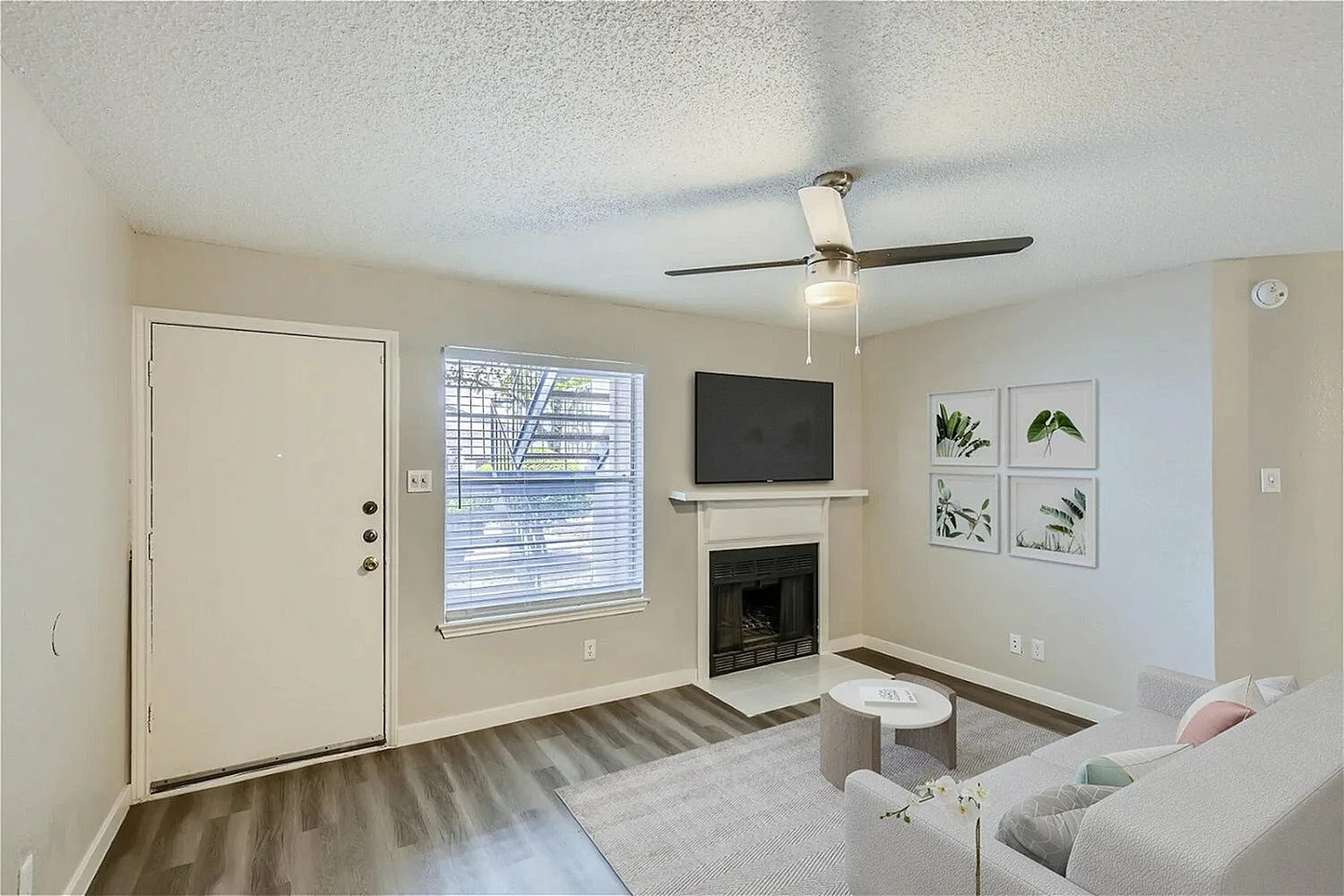 Living room, wood-style plank flooring, fireplace, ceiling fan, mounted TV