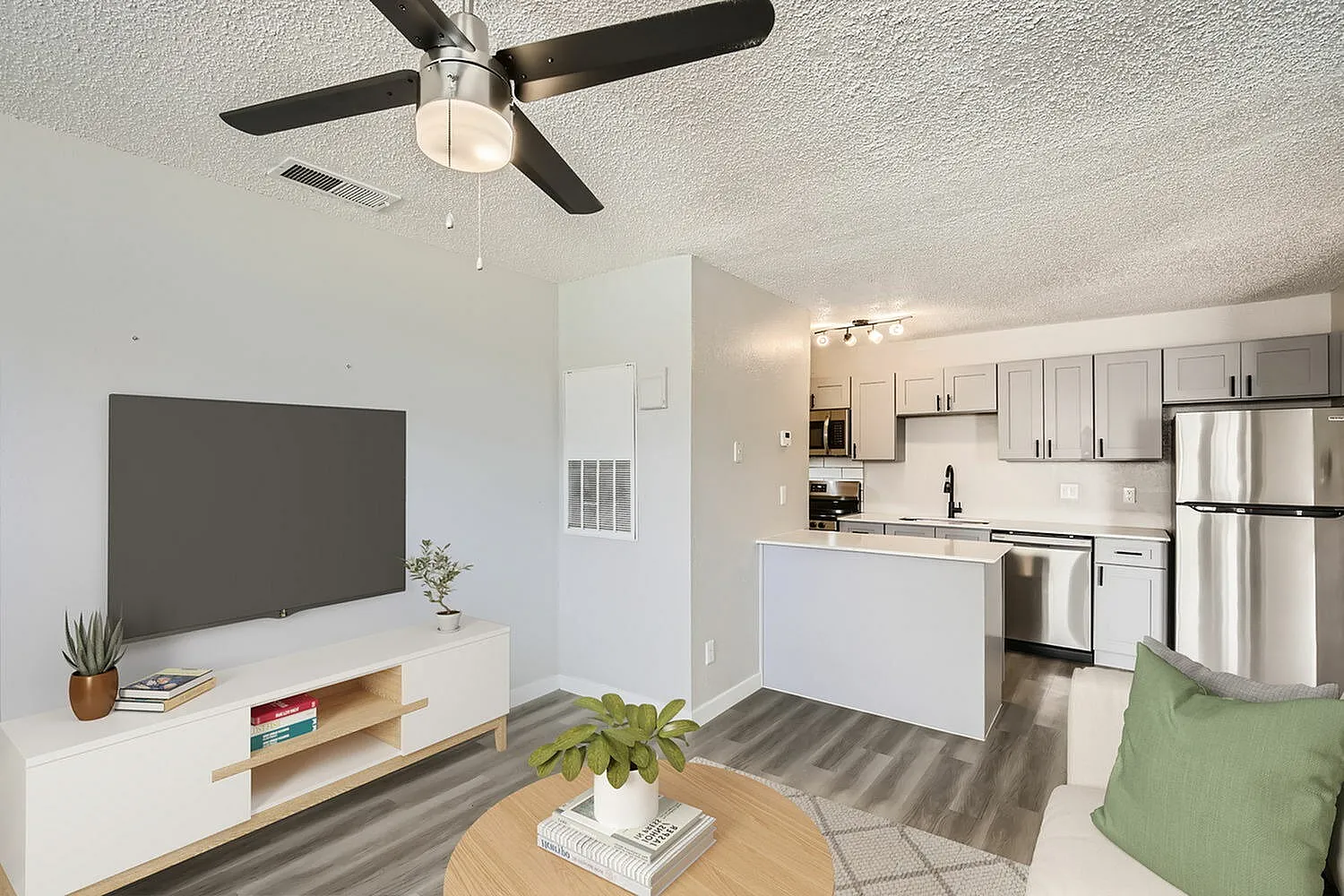 Living room and kitchen, wood-style plank flooring, ceiling fan, white cabinetry, stainless appliances