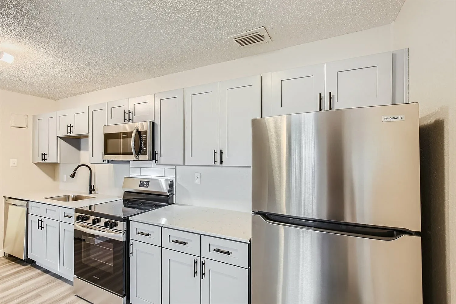 Kitchen, white shaker cabinetry, quartz countertops, stainless steel appliances, wood-style plank flooring