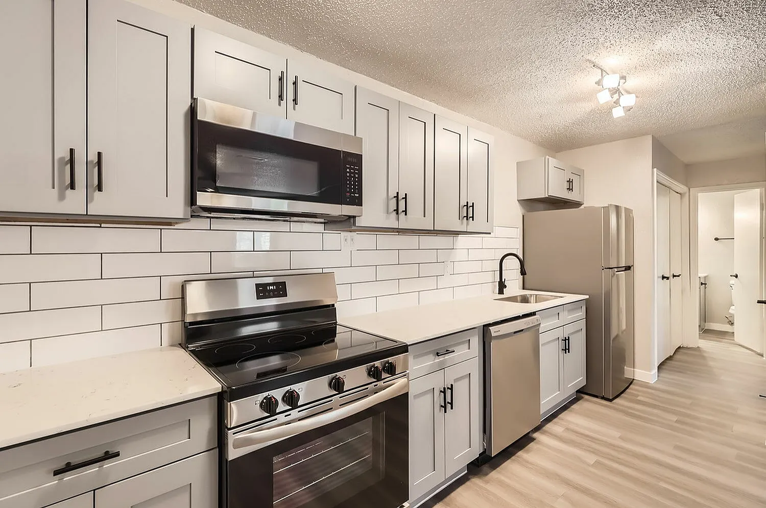 Kitchen, white shaker cabinetry, subway tile backsplash, stainless appliances, wood-style plank flooring