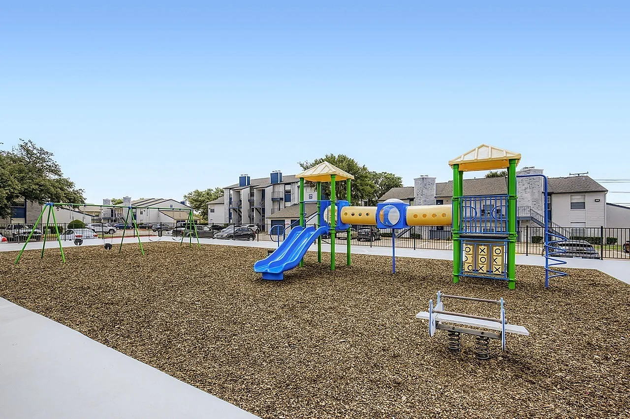 Community playground, blue slide, climbing structures, mulch ground cover, benches