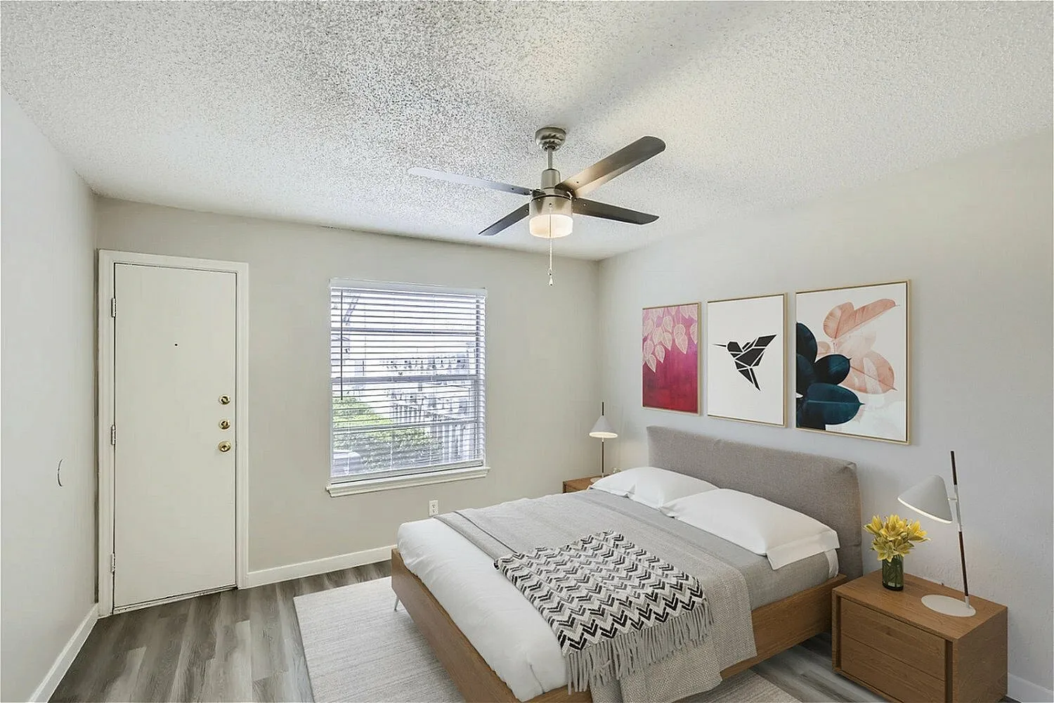 Primary bedroom, wood-style plank flooring, ceiling fan, framed wall art