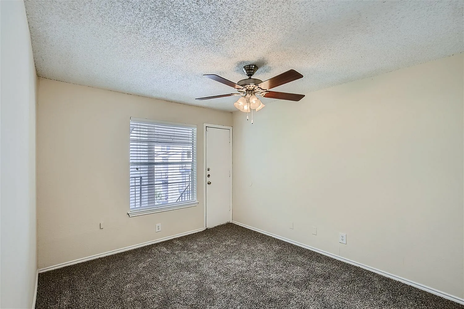 Bedroom, dark gray carpeting, ceiling fan with light fixture, entry door with blinds