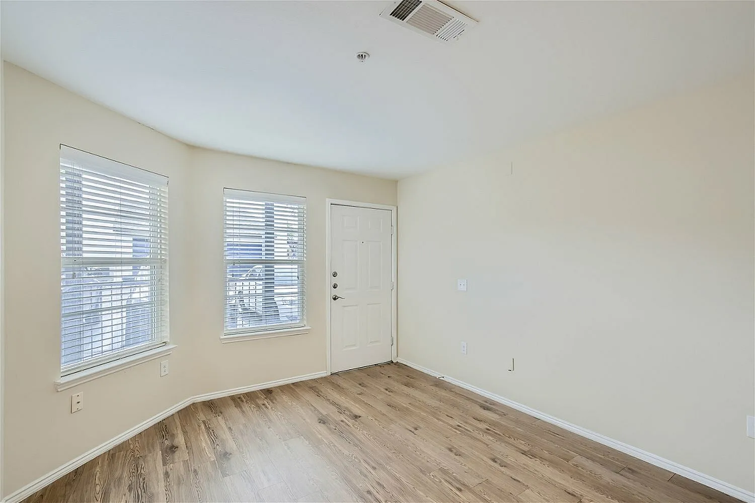 Bedroom, wood-style plank flooring, dual windows with blinds, entry door