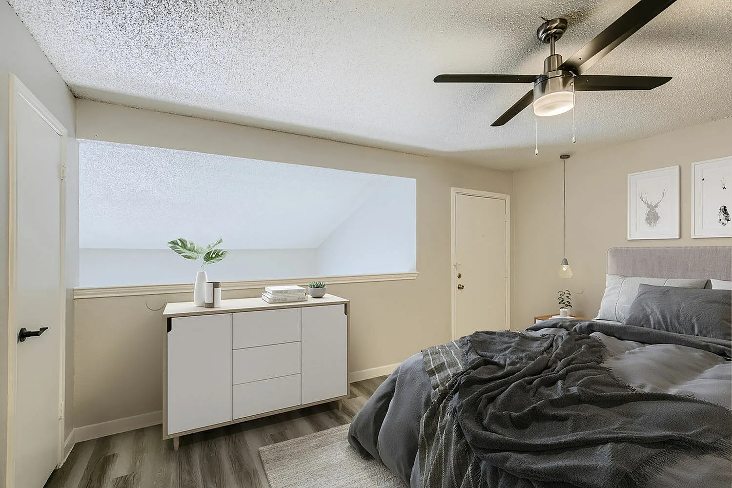 Primary bedroom, wood-style plank flooring, ceiling fan, white dresser, large window