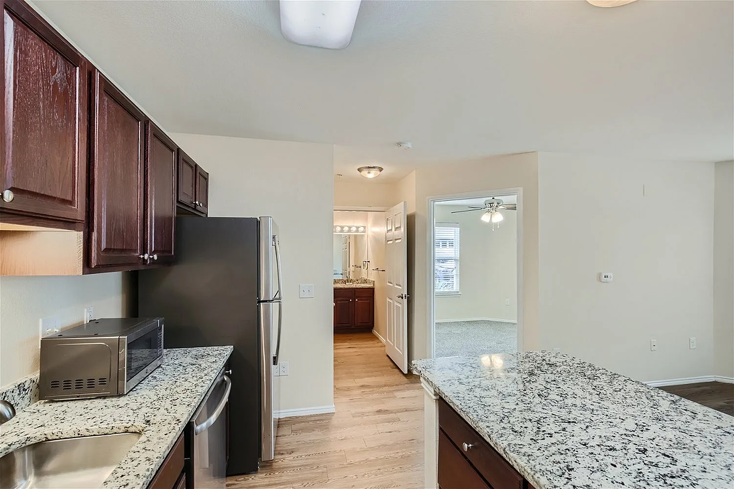 Kitchen, dark wood cabinetry, granite countertops, stainless appliances, wood-style plank flooring