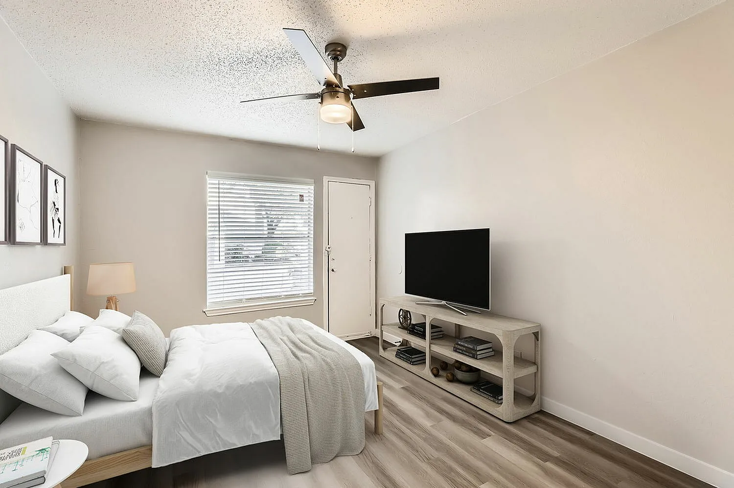 Primary bedroom, wood-style plank flooring, ceiling fan, flat-screen TV, entry door with blinds