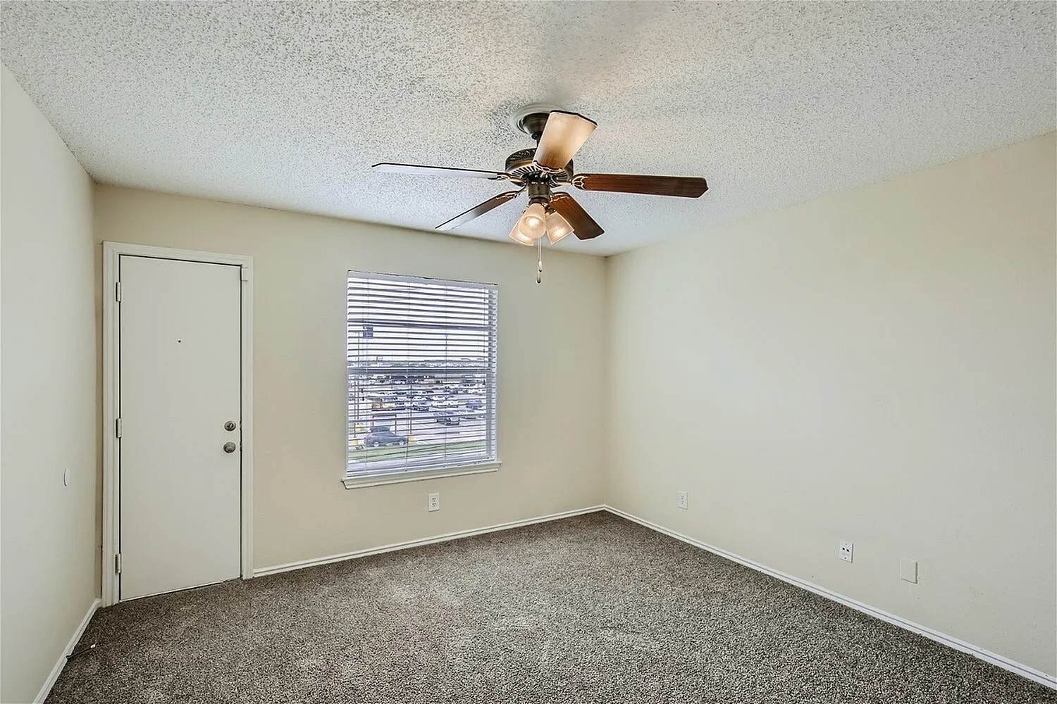 Bedroom, gray carpet flooring, ceiling fan with light fixture, window with blinds, entry door