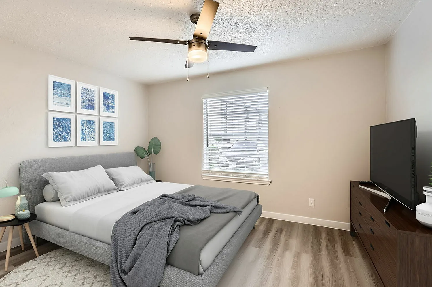 Primary bedroom, gray upholstered bed, wood-style plank flooring, ceiling fan, window with blinds