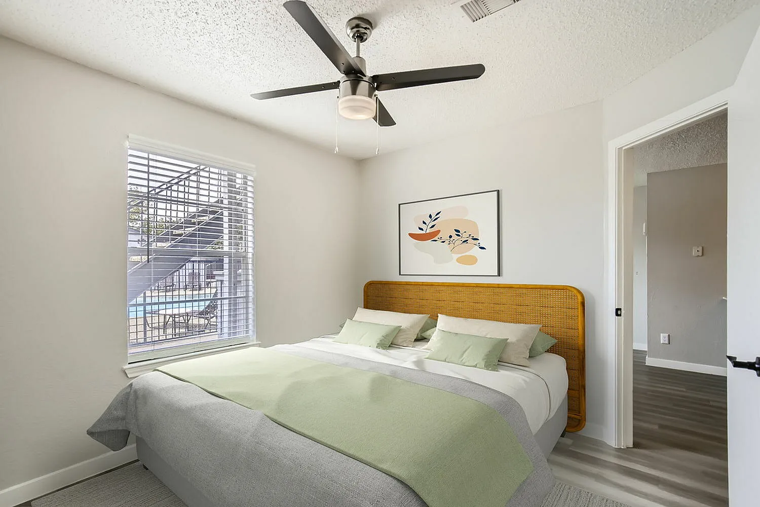 Primary bedroom, wood-style plank flooring, ceiling fan with light, wood headboard