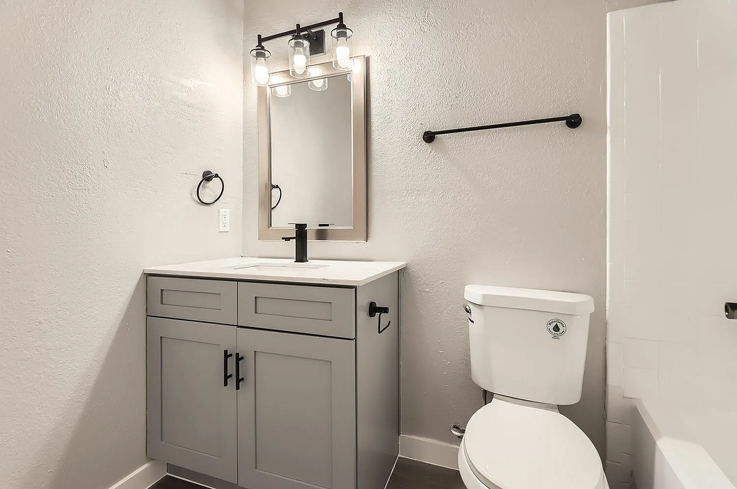 Bathroom, gray shaker cabinetry vanity, white quartz countertop, framed mirror with black vanity lighting