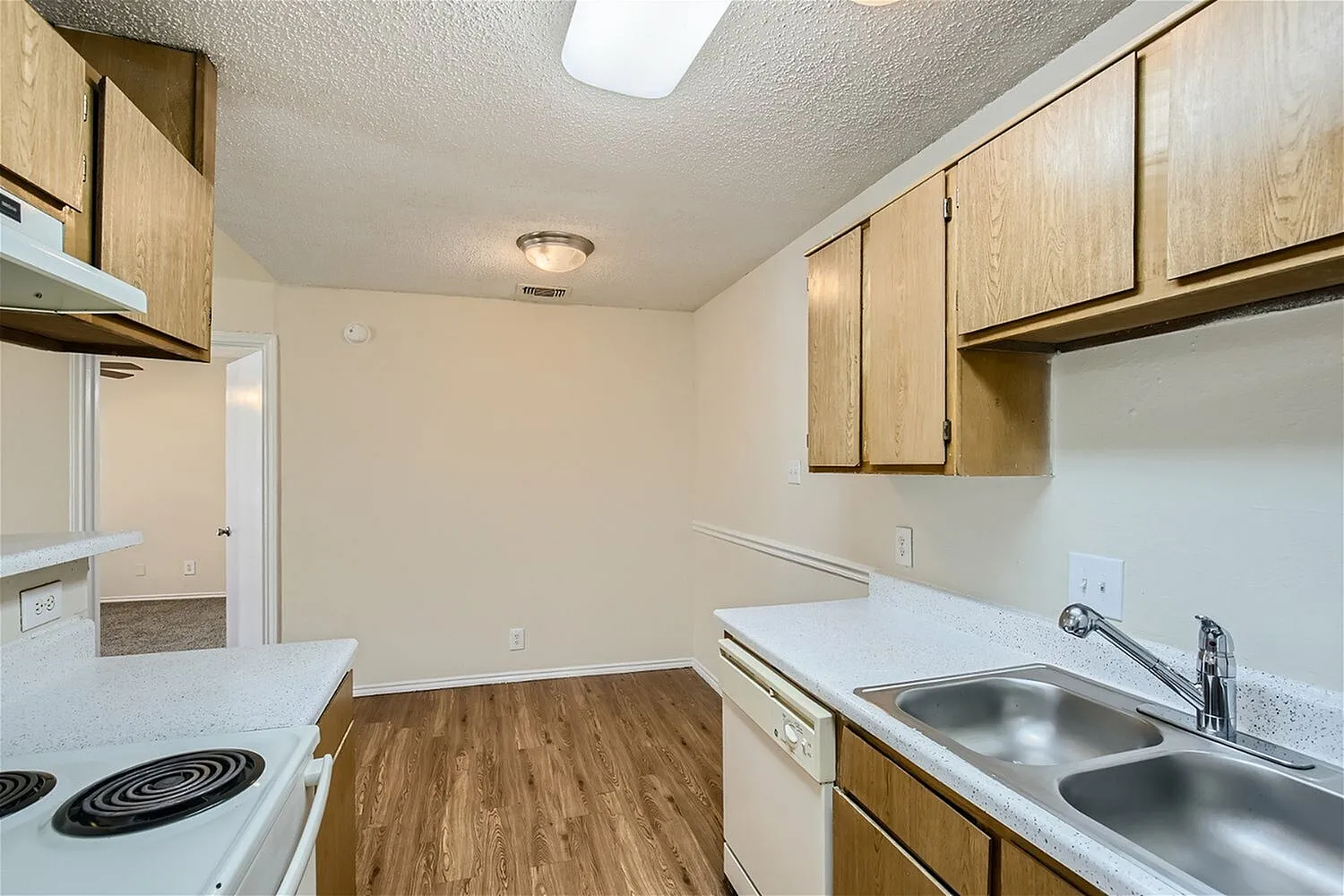 Kitchen, wood cabinetry, white countertops, stainless sink, wood-style plank flooring