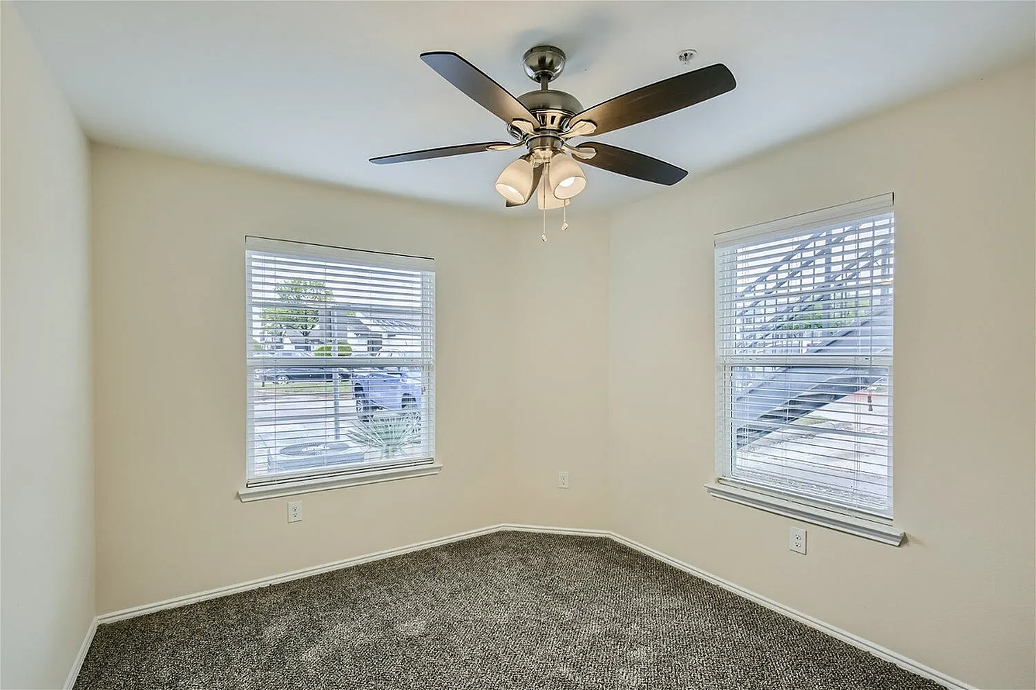 Bedroom, gray carpeting, ceiling fan with light fixture, dual windows with blinds