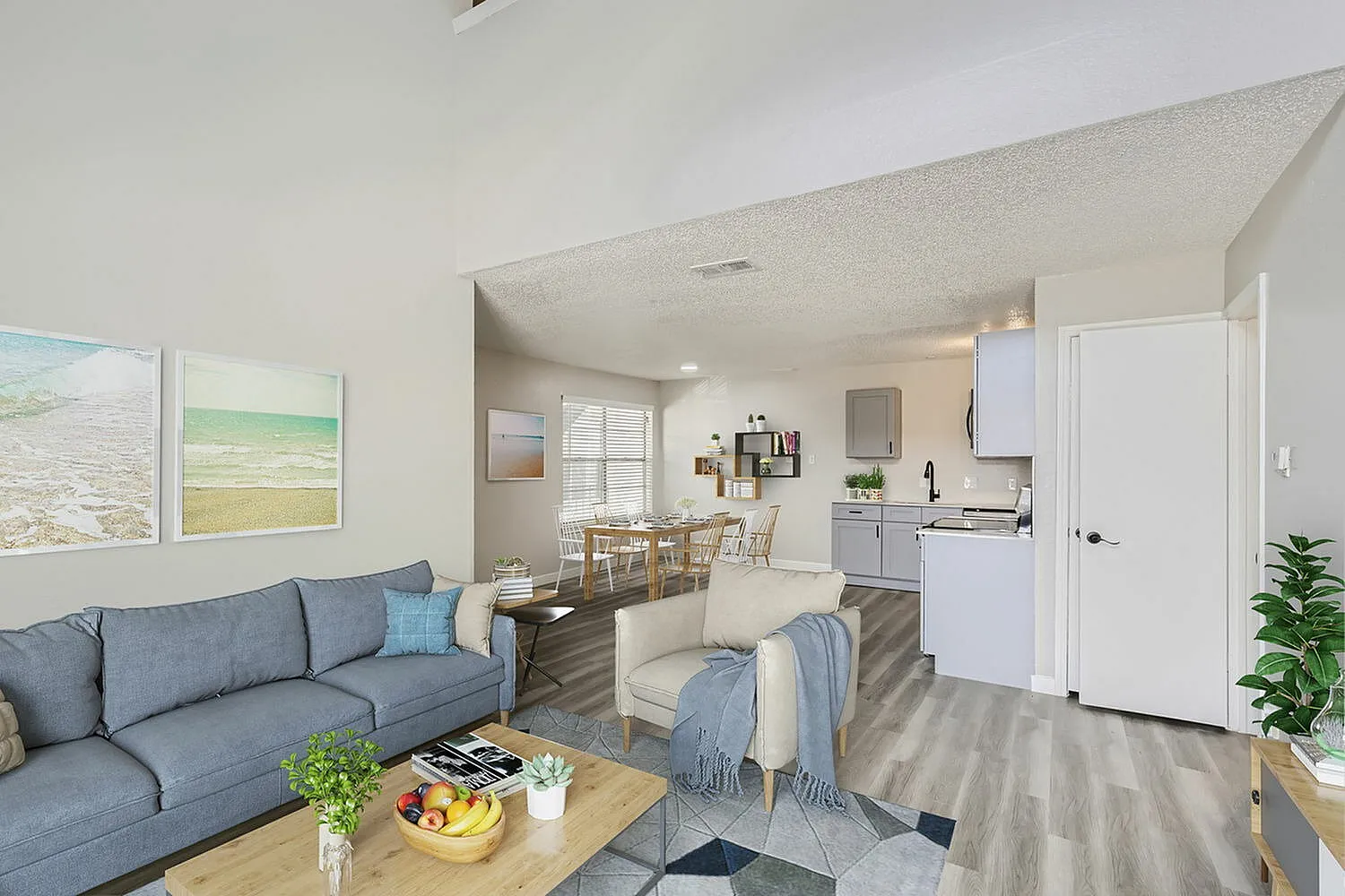 Living room and kitchen, blue upholstered sofa, wood-style plank flooring, white cabinetry