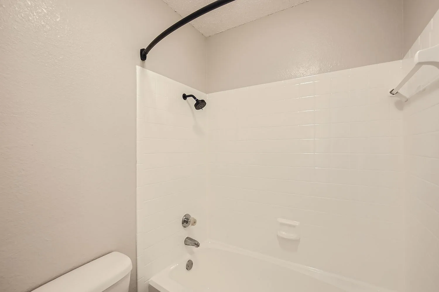 Bathroom, white subway tile walls, black curved shower rod, chrome fixtures