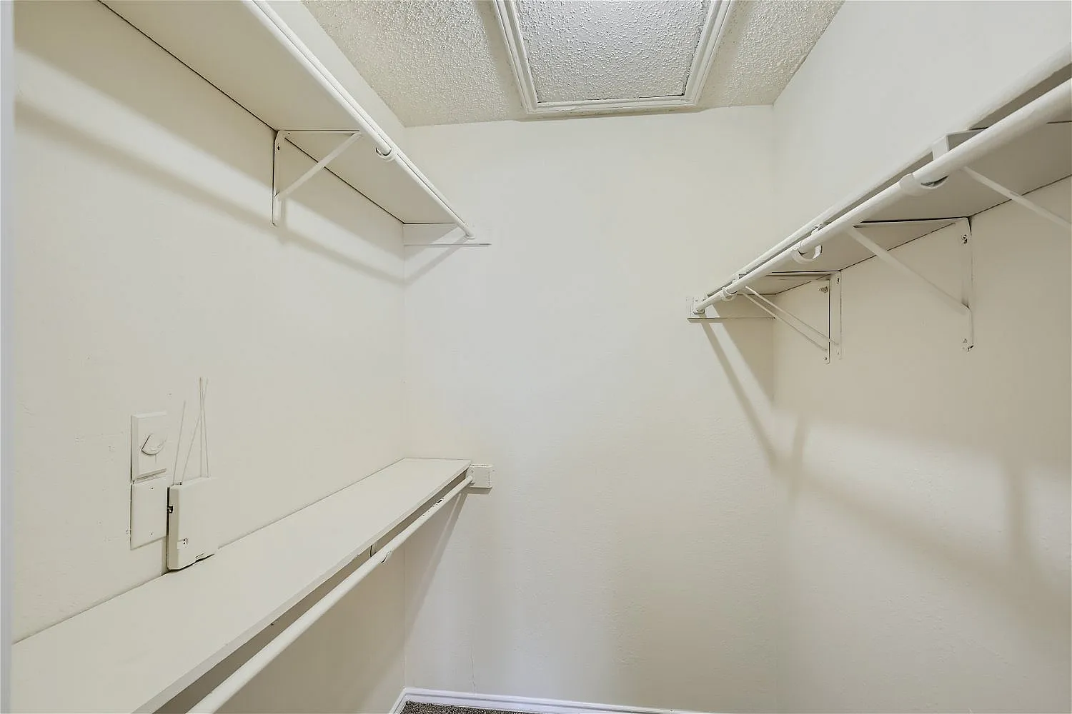 Closet interior, white walls, wire shelving, ceiling fixture, natural light