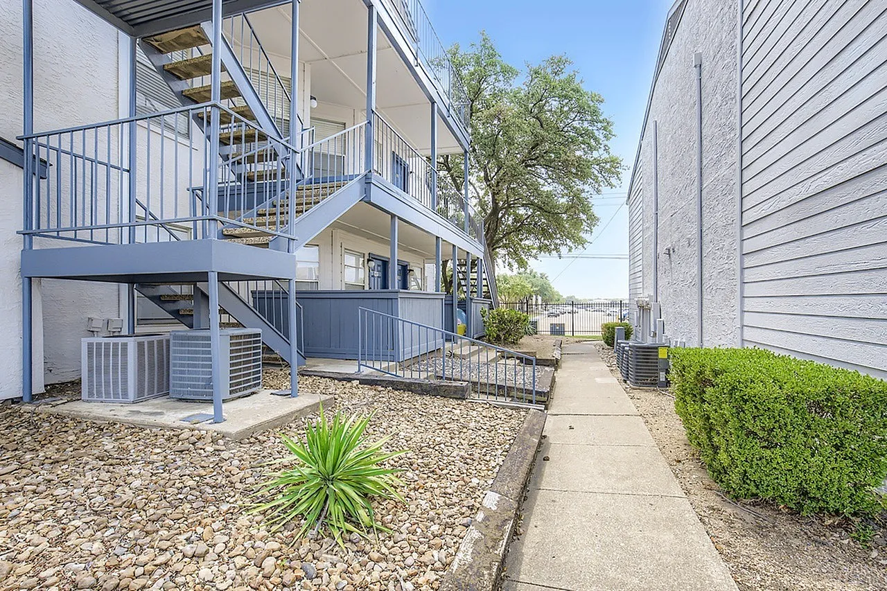 Exterior courtyard, metal railings, multi-level units, tree, gravel landscaping, shrubs