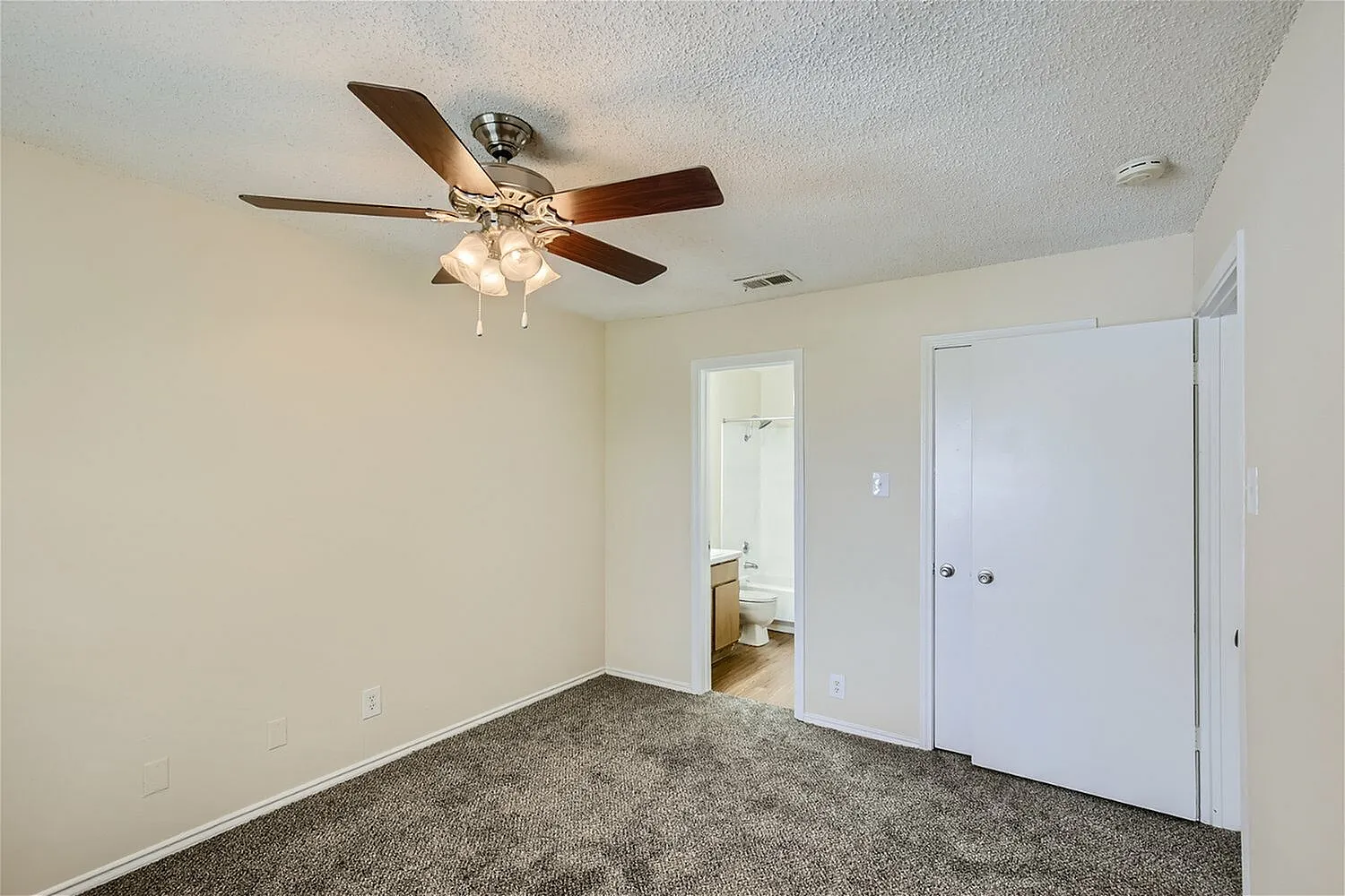 Primary bedroom, gray carpet flooring, ceiling fan with light fixture, white closet doors