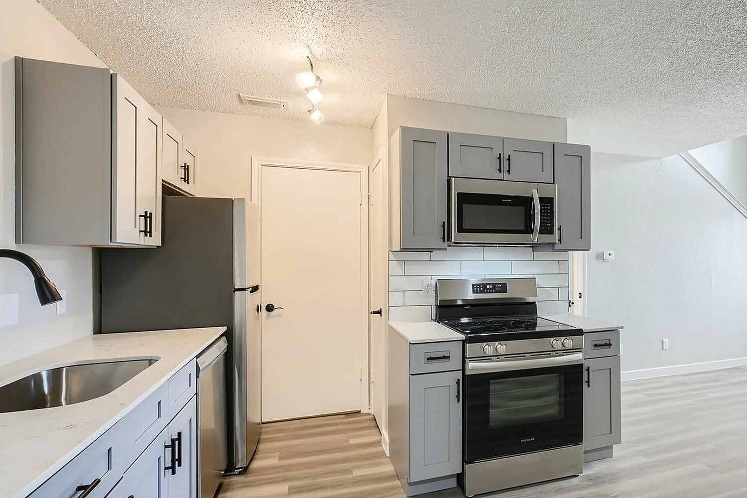 Kitchen, gray cabinetry, white subway tile backsplash, stainless steel appliances, wood-style plank flooring