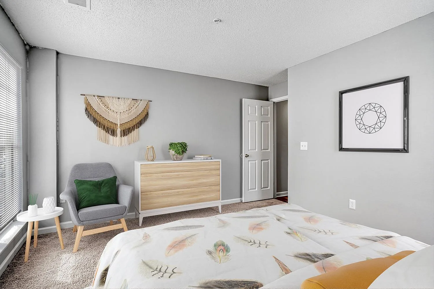 Primary bedroom, wood-style plank flooring, gray accent wall, wooden dresser, geometric bedding