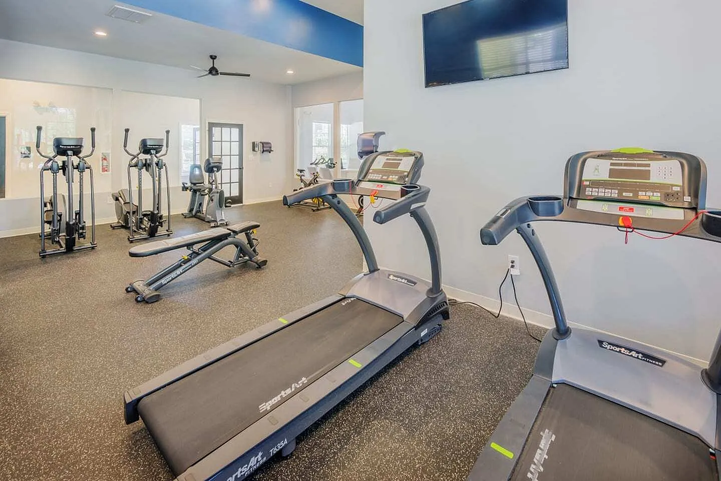 Fitness center, treadmills, stationary bikes, elliptical machines, mounted TV, carpet flooring