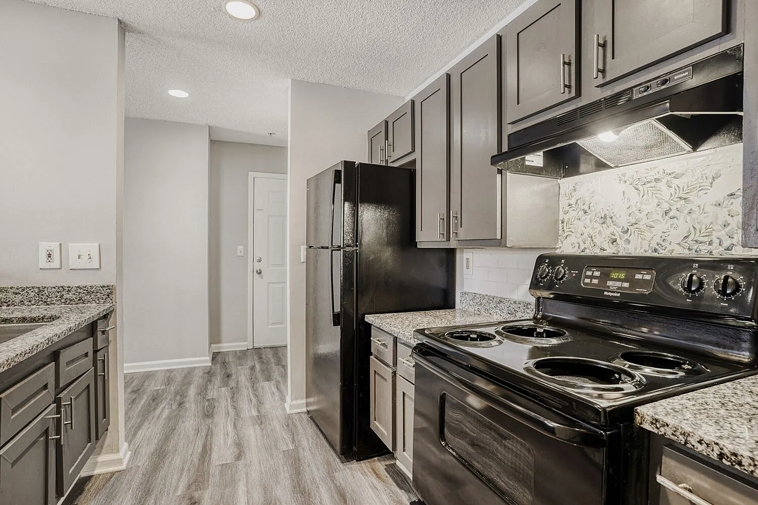 Kitchen, gray cabinetry, granite countertops, black stainless appliances, wood-style plank flooring