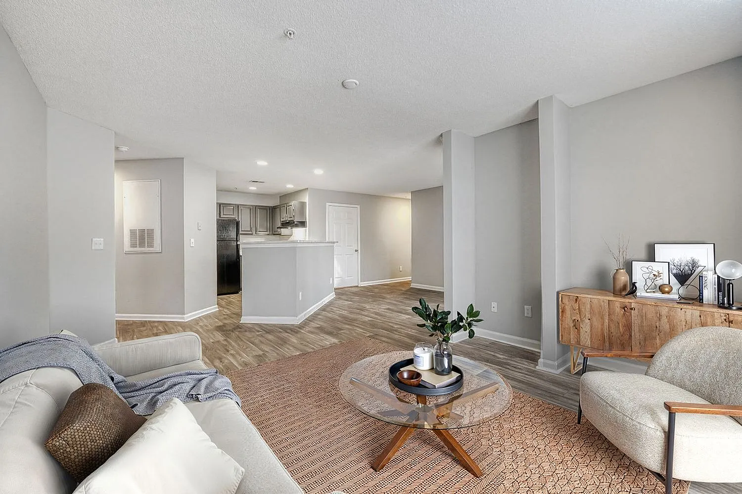 Open concept living room, wood-style plank flooring, round accent table, white cabinetry