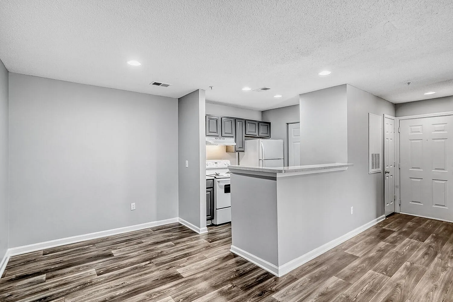 Kitchen with white cabinetry and stainless appliances, wood-style plank flooring, white painted walls
