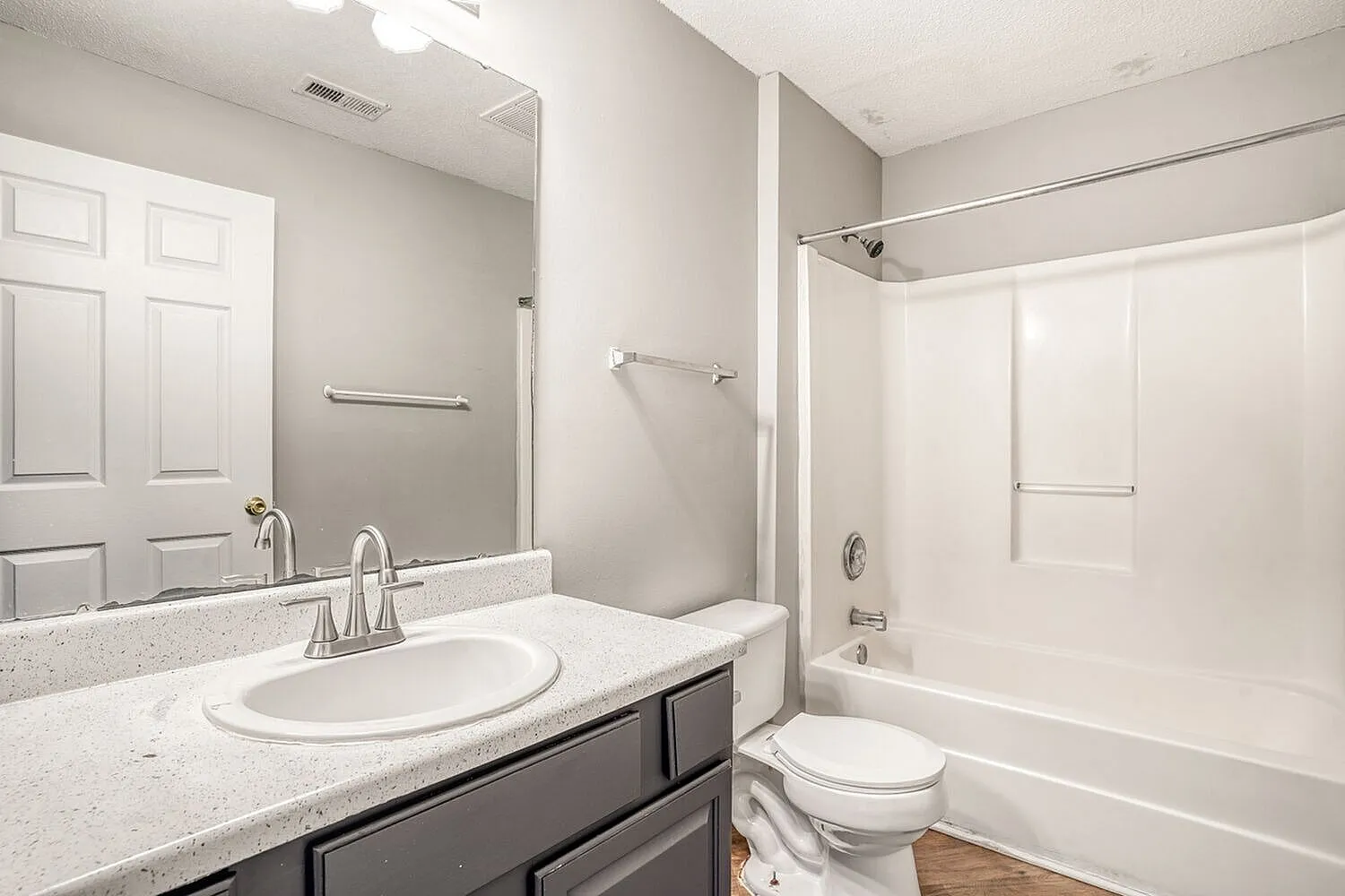 Primary bathroom, speckled quartz countertops, dark cabinetry, white subway tile surround