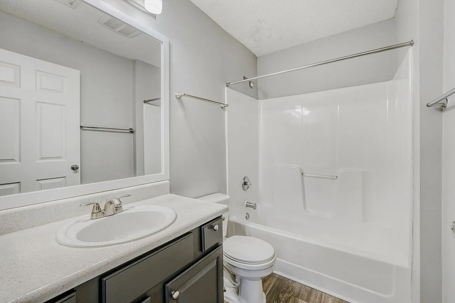 Bathroom, white round sink, dark cabinetry, white subway tile surround, wood-style plank flooring