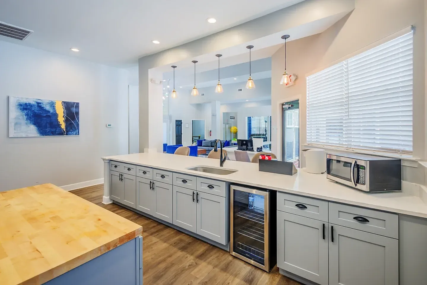 Kitchen with gray cabinetry, quartz countertops, stainless appliances, wood-style plank flooring, pendant lighting, yellow island